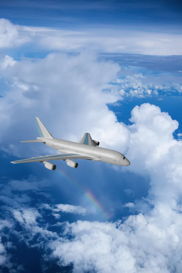 © shirophoto - stock.adobe.com Flugzeug fliegt über Wolken mit Regenbogen im Hintergrund.