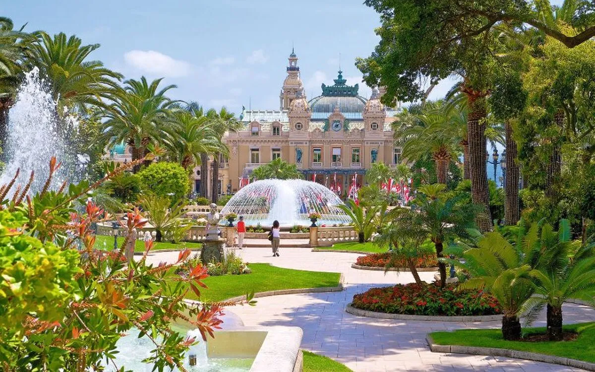 Historisches Casino Monte Carlo mit Springbrunnen und Parkanlage, Touristen im Vordergrund.
