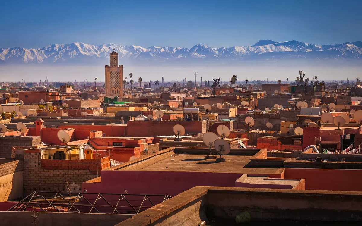 Panorama von Marrakesch mit Blick über die Dächer der Stadt, im Hintergrund das Atlasgebirge.