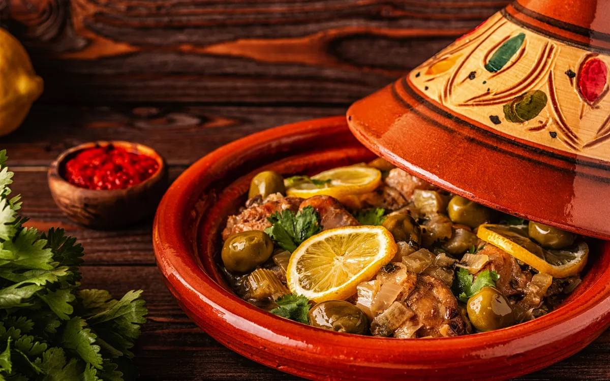 Marokkanischer Tajine mit Hähnchen und Zitronenscheiben in einer verzierten Tonform.