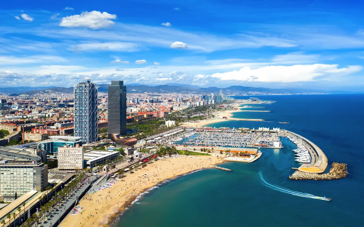 Stadtansicht mit Strand, Meer und Hochhäusern unter blauem Himmel.