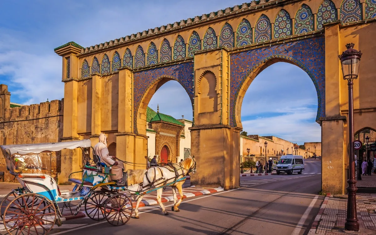 Kutsche unter orientalischem Torbogen bei Sonnenuntergang.