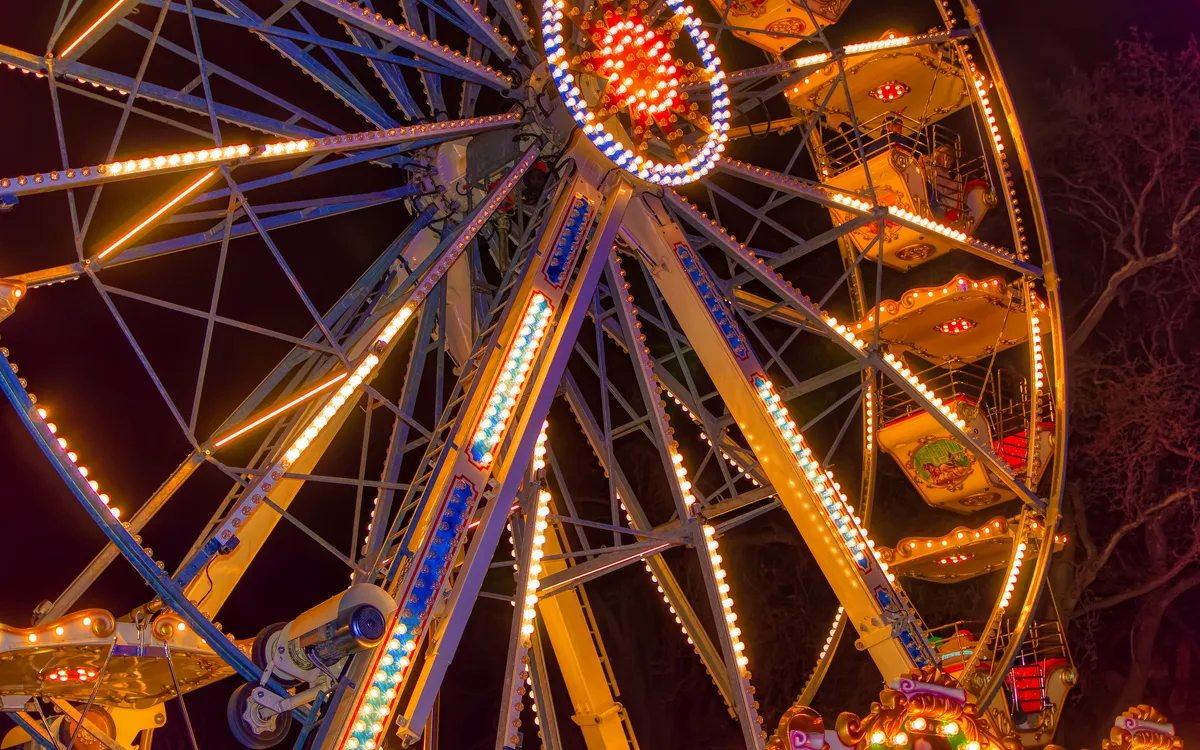 Riesenrad bei Nacht mit Beleuchtung vor dunkelrotem Himmel.