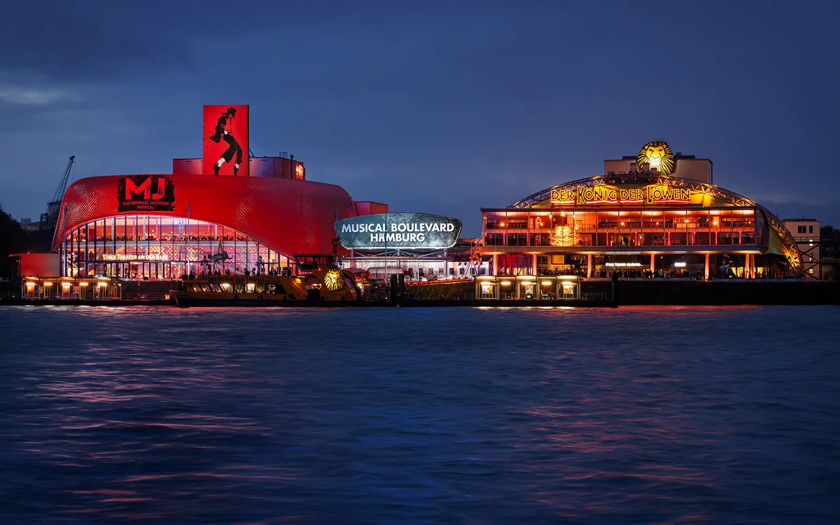 Beleuchtetes Musicaltheater am Hamburger Hafen bei Nacht.