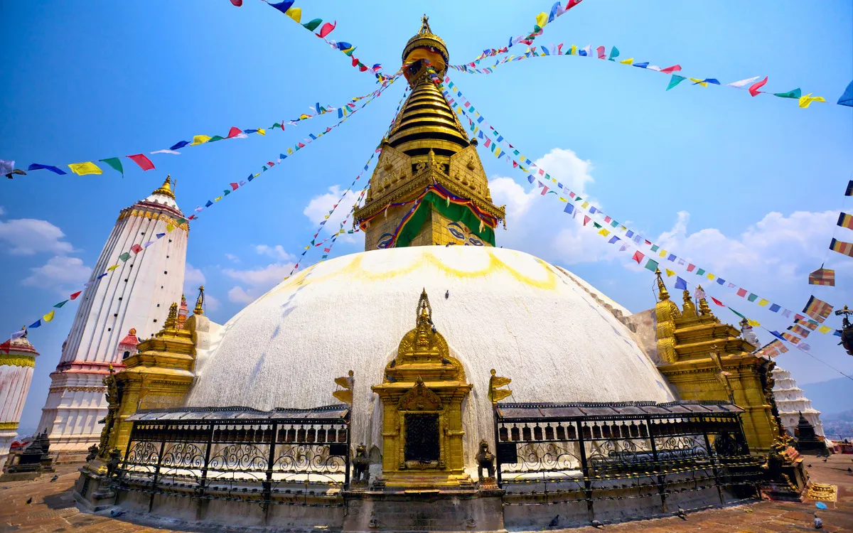 Swayambhunath Stupa mit Gebetsfahnen bei blauem Himmel.