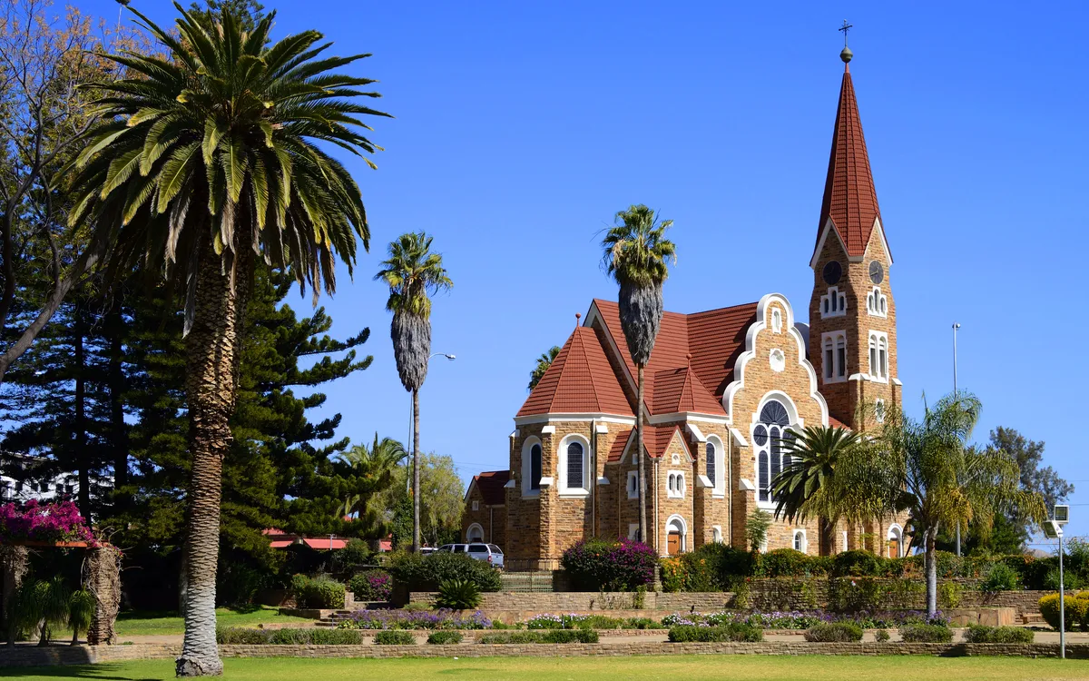 Christuskirche in Windhoek, Namibia umgeben von Palmen und einem klaren blauen Himmel.