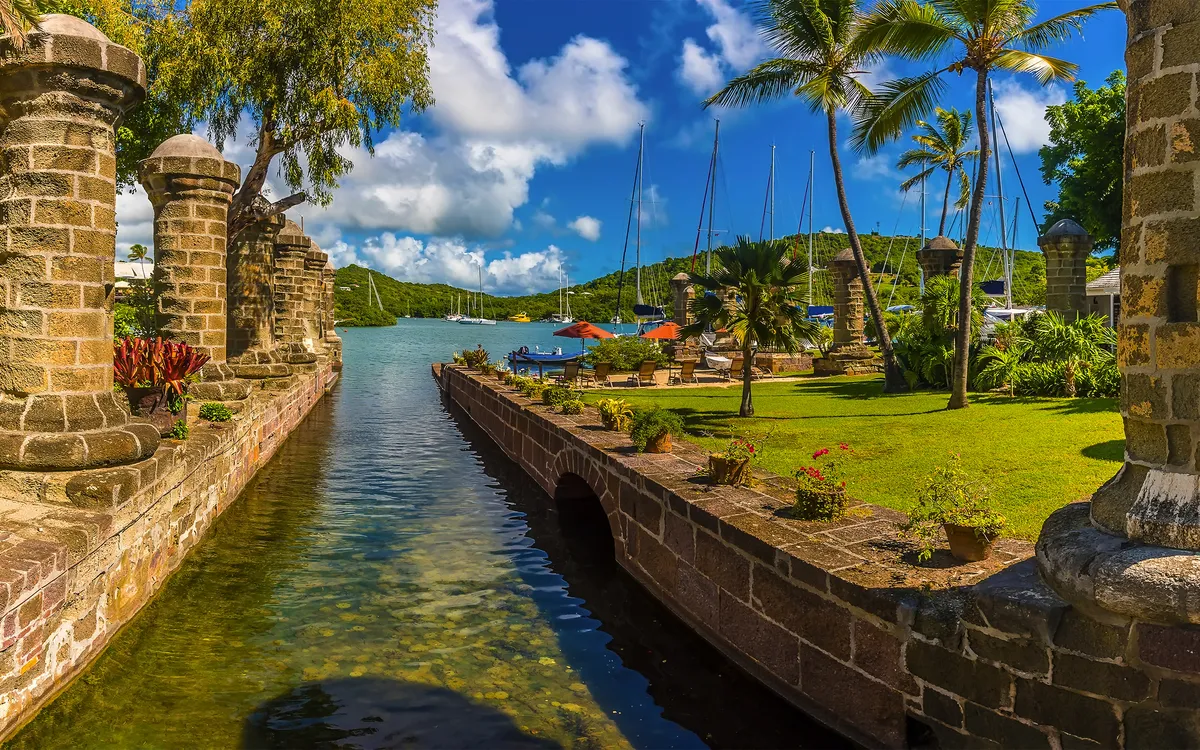 English Harbour in Antigua mit historischem Dock, üppiger tropischer Vegetation und Segelbooten.