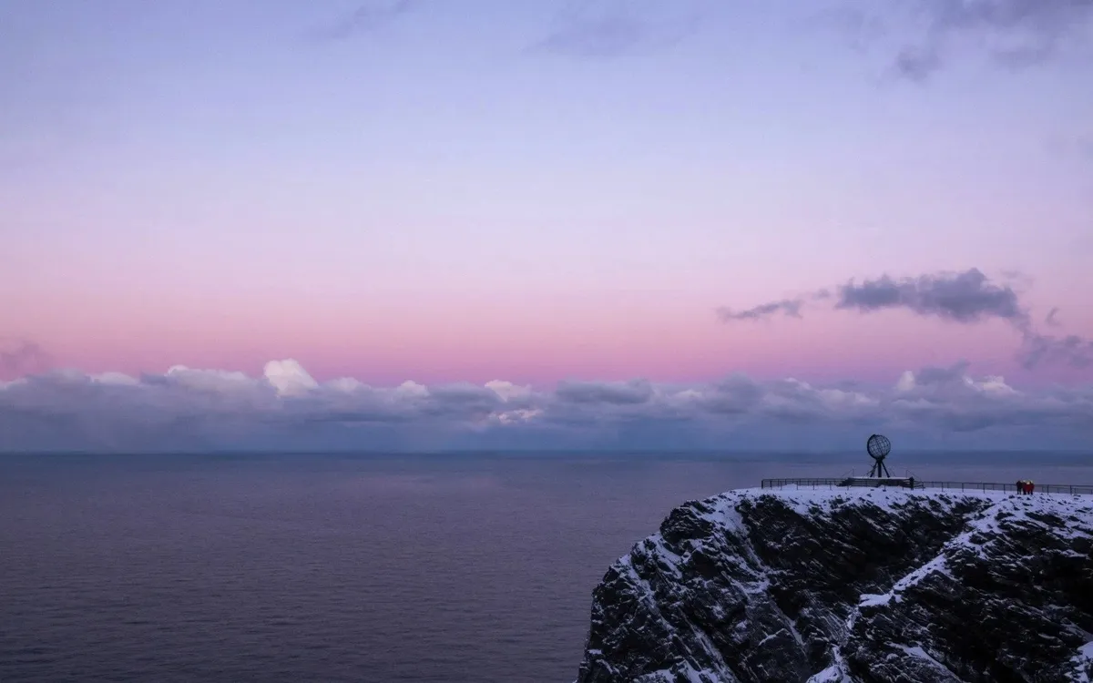 Schneebedeckte Klippe am Nordkap, Norwegen, bei Sonnenuntergang über dem Meer.