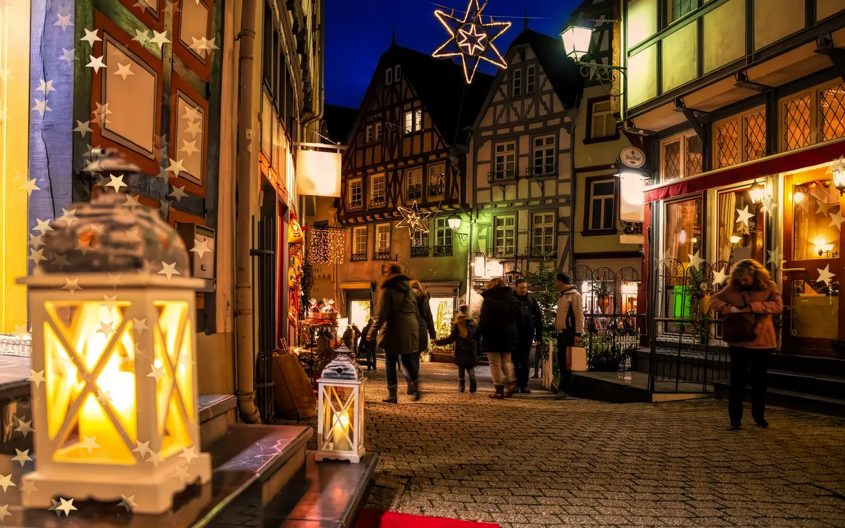 Beleuchtete Altstadtgasse mit Fachwerkhäusern und Laternen in der Abenddämmerung.