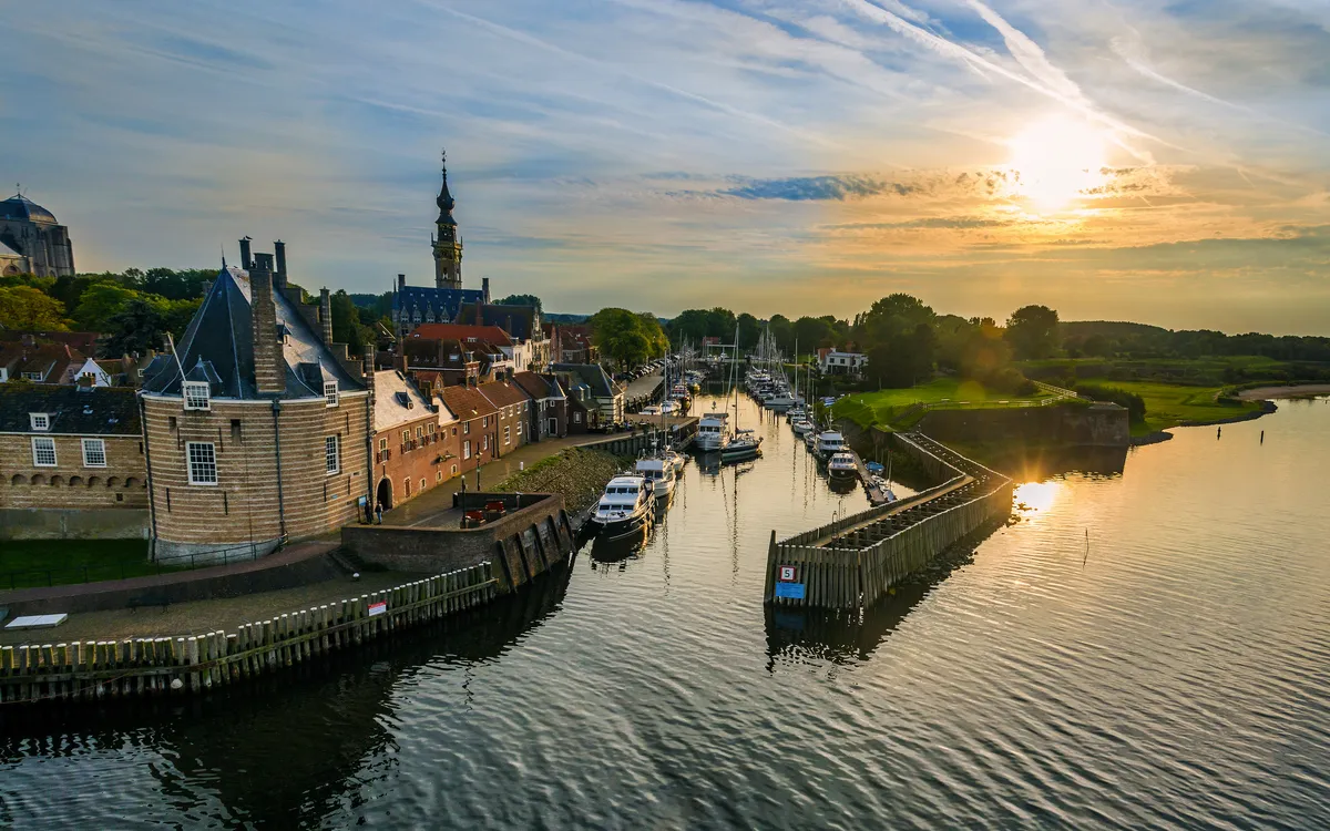 Historische Stadtansicht bei Sonnenuntergang mit Hafen und Wasserstraße.