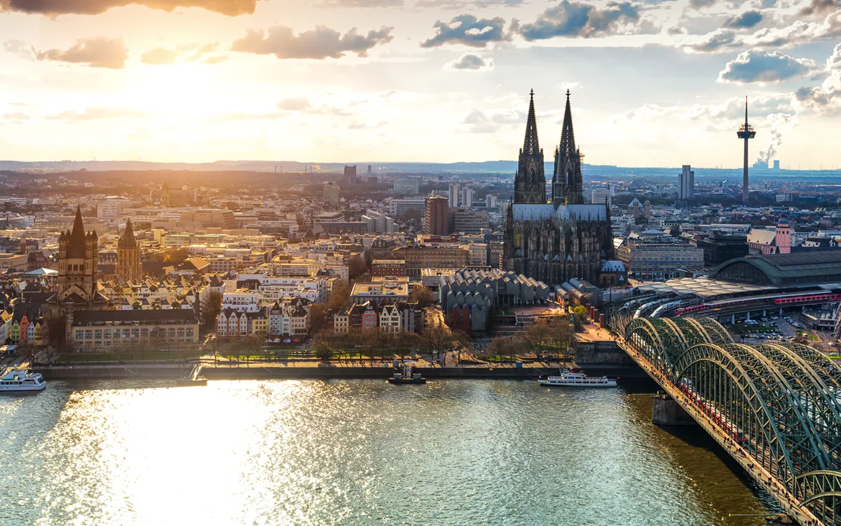 Kölner Skyline mit Dom, Rhein und Hohenzollernbrücke bei Sonnenuntergang.
