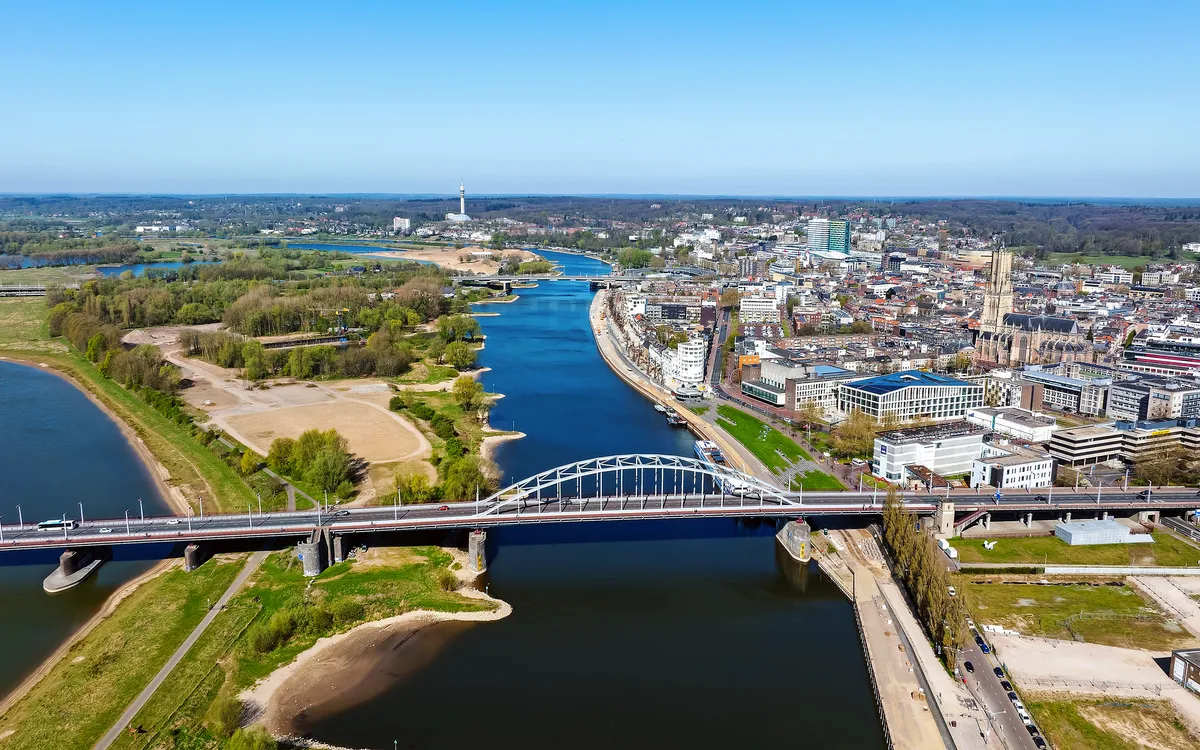 Luftaufnahme einer Stadt mit Fluss, Brücke und grünen Landschaften.