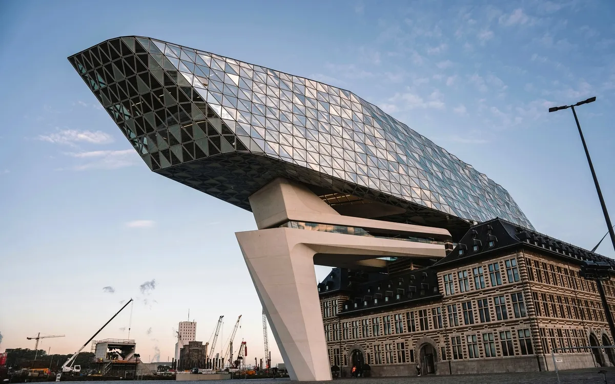 Modernes Gebäude mit gläserner Struktur auf altem Backsteingebäude.