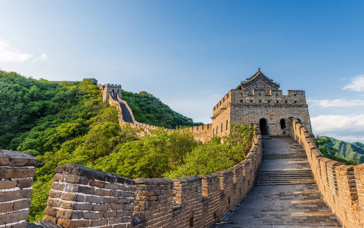 Chinesische Mauer mit blühenden Bäumen unter einem klaren blauen Himmel.