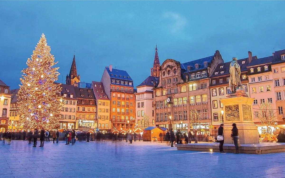 Weihnachtsmarkt auf einem Platz in Straßburg mit hellbeleuchtetem Baum
