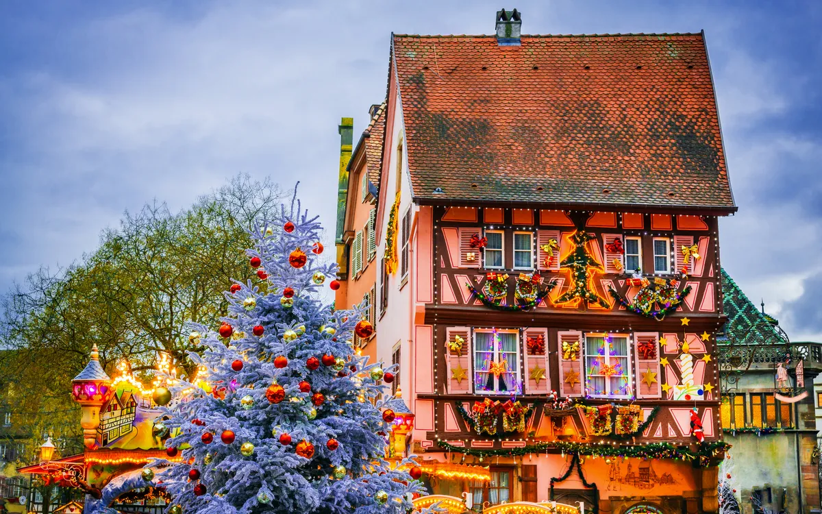 Fachwerkhaus mit Weihnachtsdekoration und geschmücktem Tannenbaum im Winter.