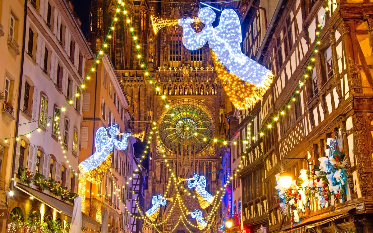 Straßenbeleuchtung mit Engelmotiven vor einer Kathedrale in festlicher Nachtaufnahme