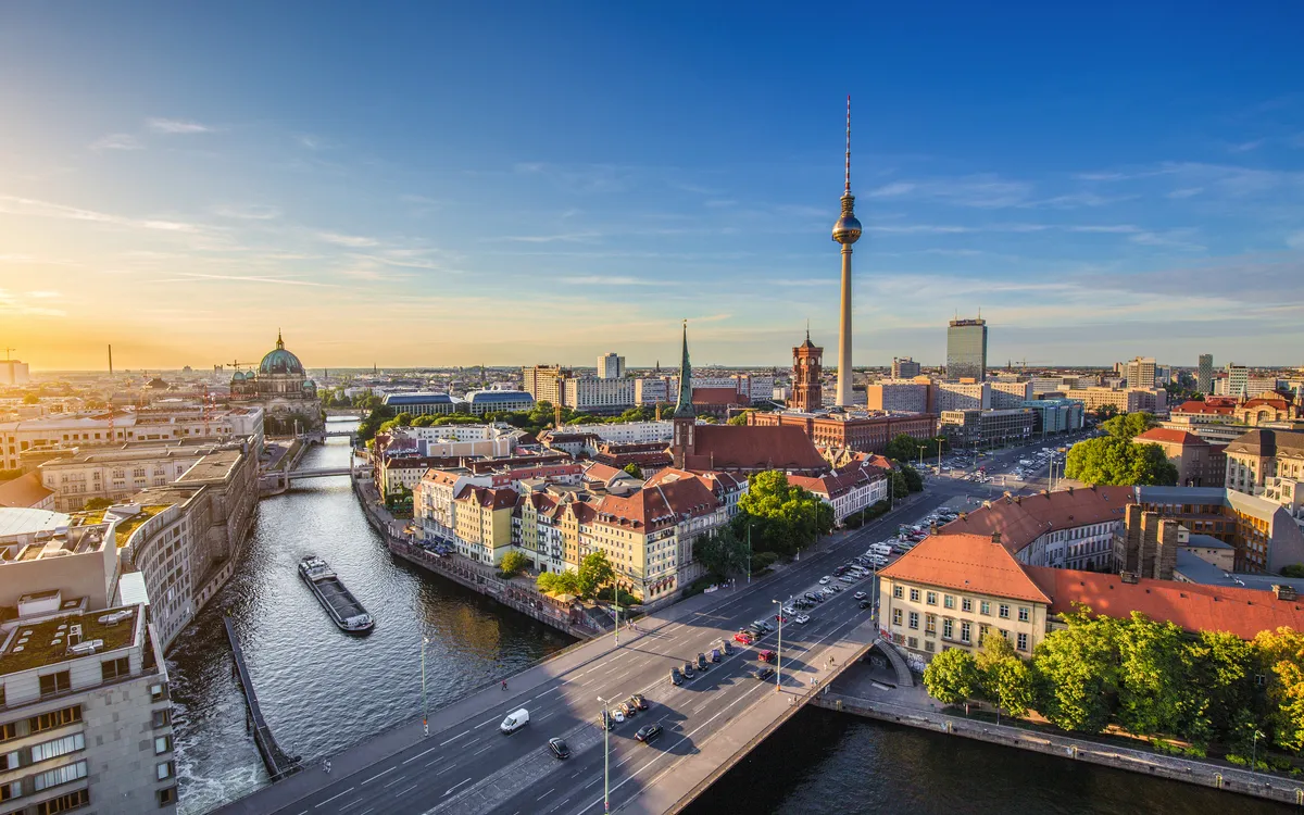 Stadtbild von Berlin mit Fernsehturm und Fluss bei Sonnenuntergang.