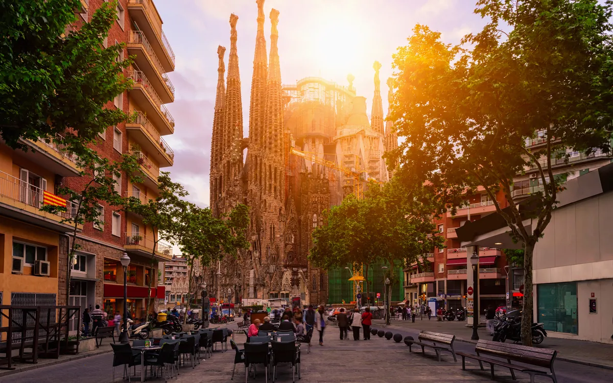 Eine belebte Straße mit einer beeindruckenden Kirche im Hintergrund bei Sonnenuntergang.