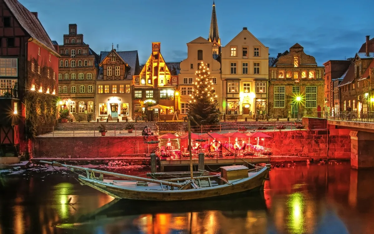 Abendstimmung in einer malerischen Altstadt mit Weihnachtsbeleuchtung am Fluss.