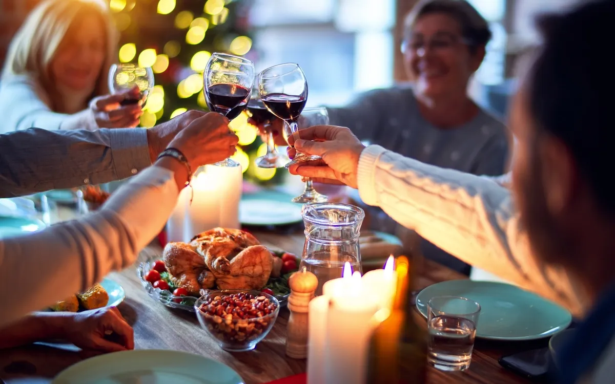 Menschen stoßen mit Weingläsern an einem festlichen Tisch an.
