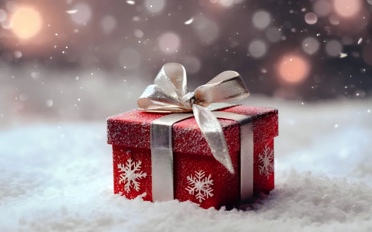 Rote Geschenkbox mit Schleife im Schnee, weihnachtlich dekoriert.