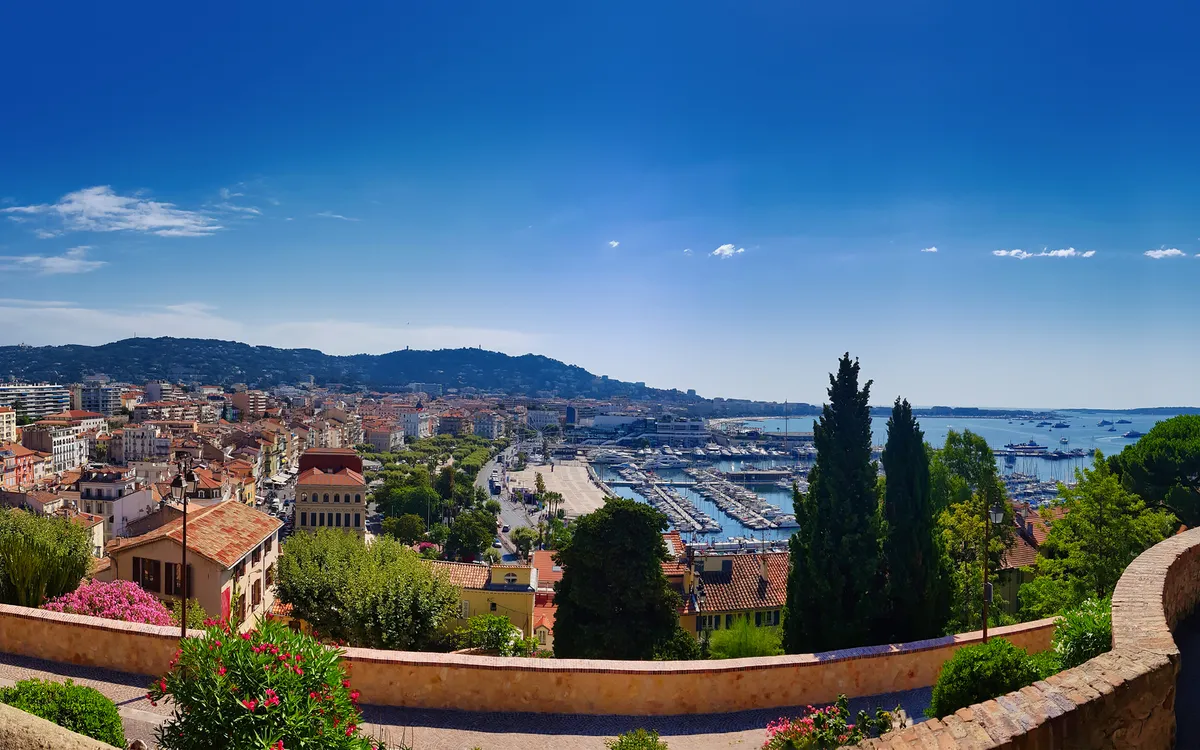 Panorama einer Küstenstadt mit Hafen und umliegenden Hügeln unter klarem Himmel.