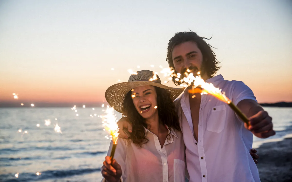 Paar am Strand bei Sonnenuntergang mit Wunderkerzen