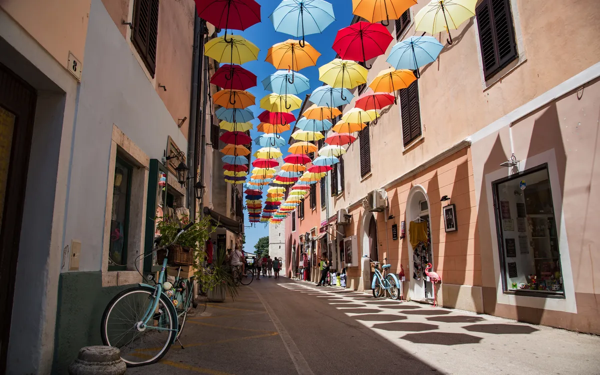 Gasse in Novigrad mit bunten Schirmen über der Straße