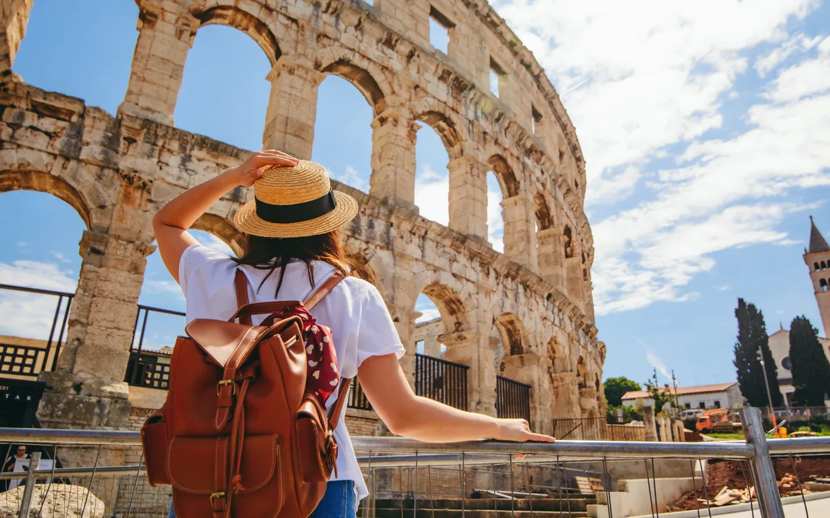 Frau mit Hut und Rucksack bewundert das Amphitheater in Pula, Kroatien.