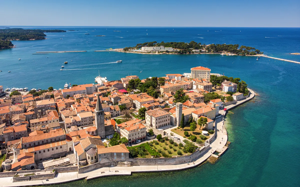 Luftaufnahme einer Küstenstadt mit historischen Gebäuden und blauem Meer.