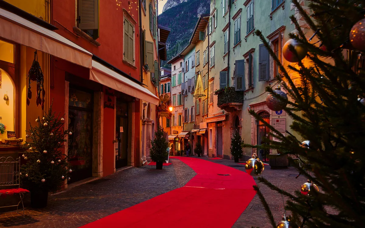 Eine festlich beleuchtete Straße in einer europäischen Altstadt bei Dämmerung.