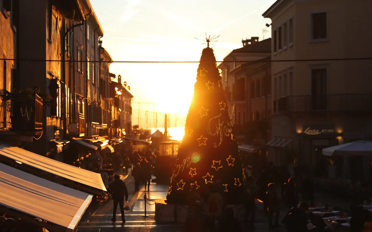 Straßenszene bei Sonnenuntergang mit Weihnachtsbaum in der Mitte.