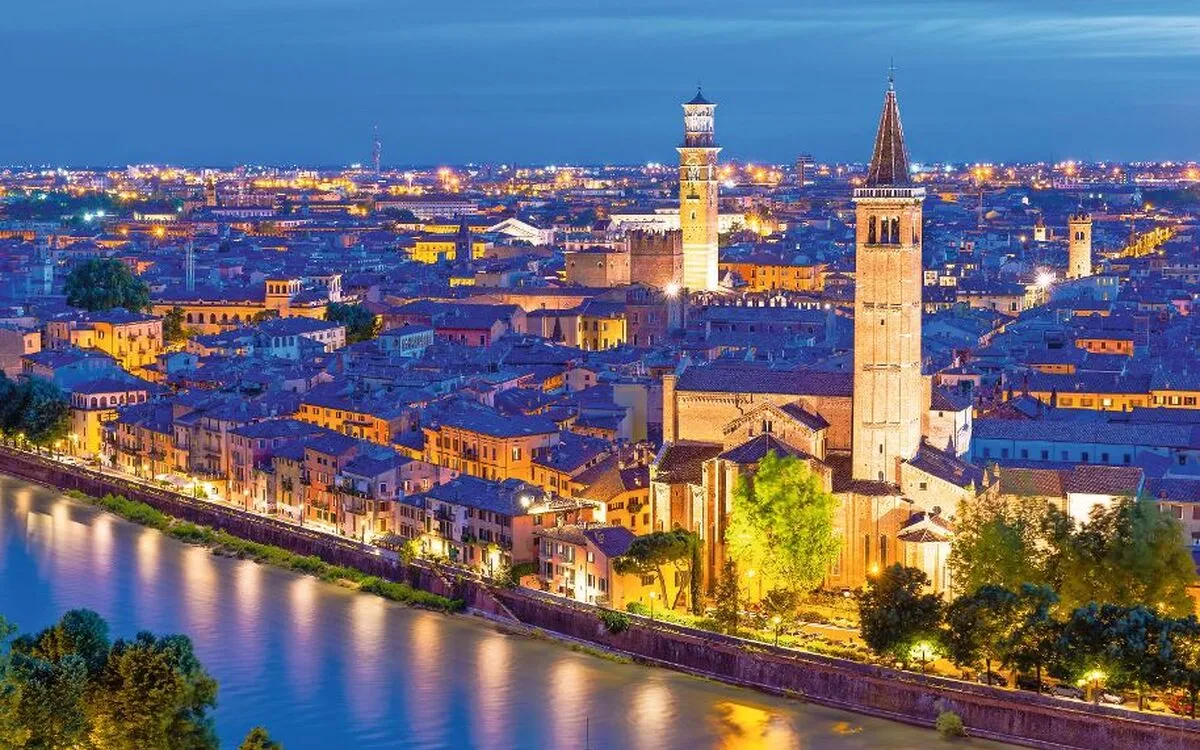 Stadtansicht von Verona bei Nacht mit Dom und Fluss Etsch im Vordergrund.