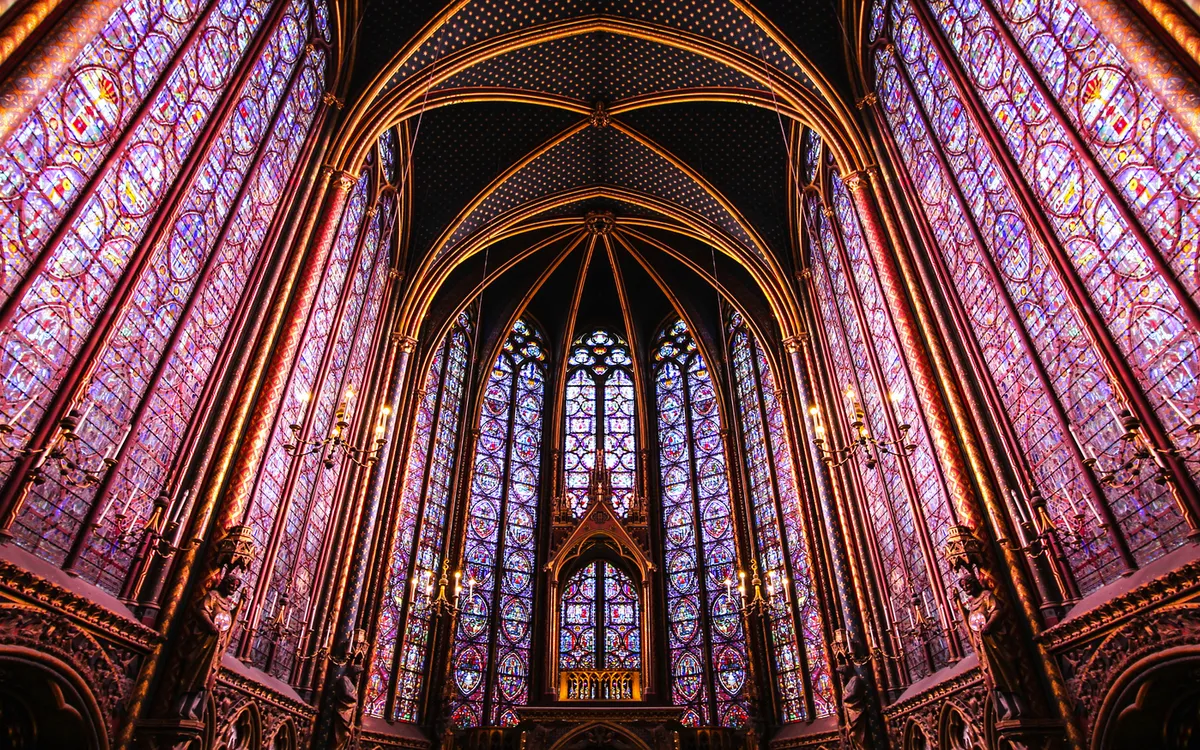 Innenansicht einer gotischen Kathedrale mit bunten Glasfenstern und Spitzbögen.