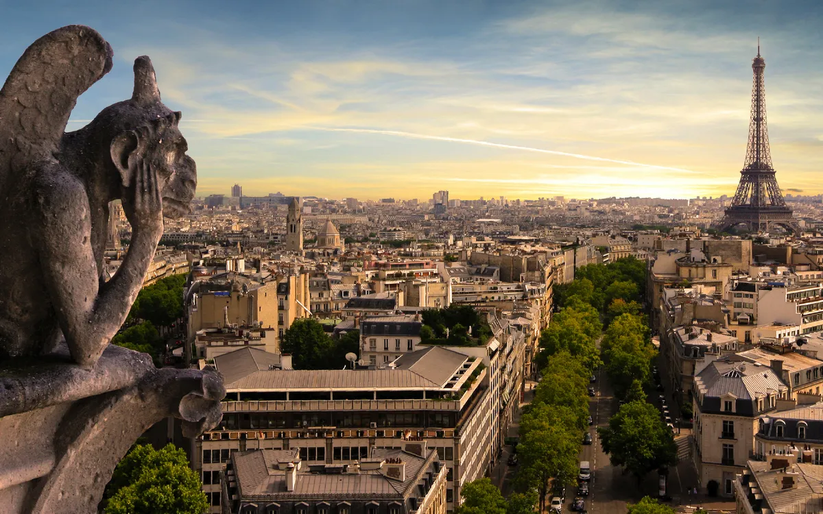 Blick auf Paris mit Eiffelturm und Wasserspeier im Vordergrund bei Sonnenuntergang.
