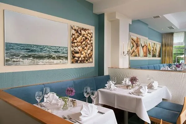 Elegantes Restaurant mit gedeckten Tischen, Wandbildern und blauer Sitzbank.