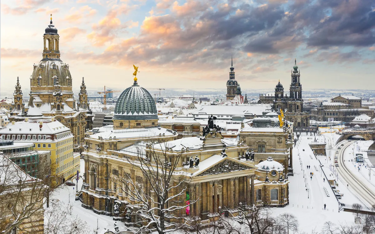 Verschneite Stadtansicht mit historischen Gebäuden bei Sonnenuntergang.