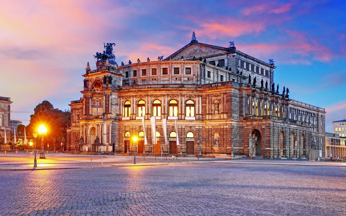 Historisches Gebäude bei Sonnenuntergang mit beleuchteten Fenstern.