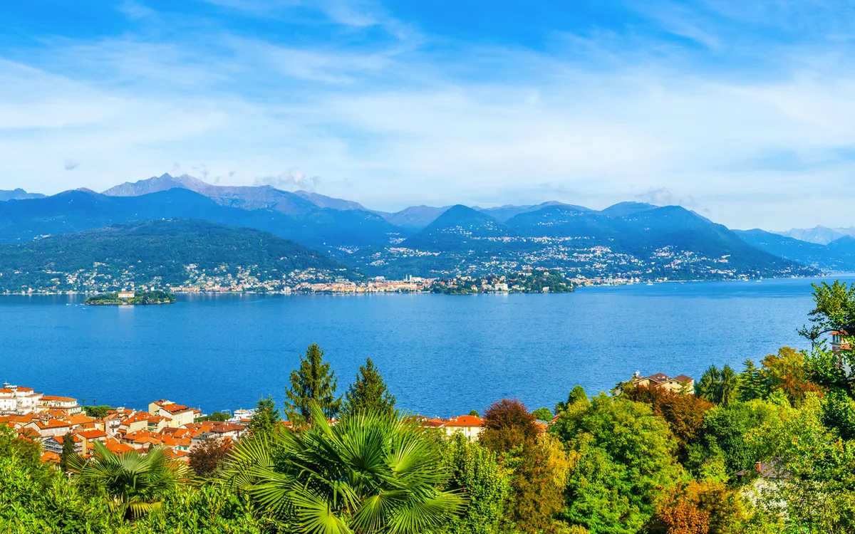 Panorama eines Sees mit Bergen und einer Stadt im Hintergrund bei klarem Wetter.