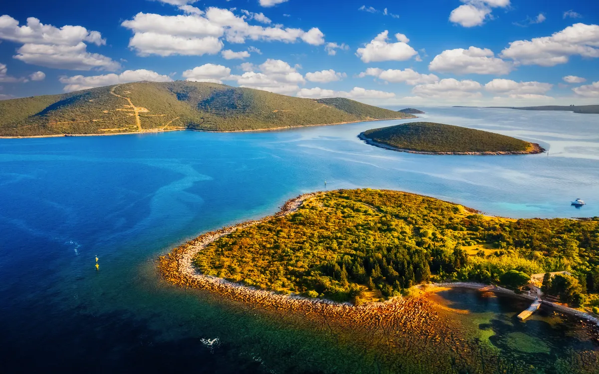 Luftaufnahme einer Küstenlandschaft mit Inseln und klarem blauen Wasser.