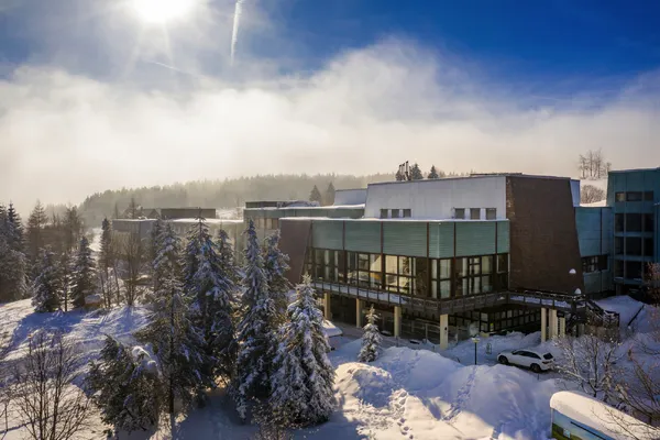 Außenansicht des Ahorn Waldhotels Altenberg im Winter mit Schnee und Bäumen.
