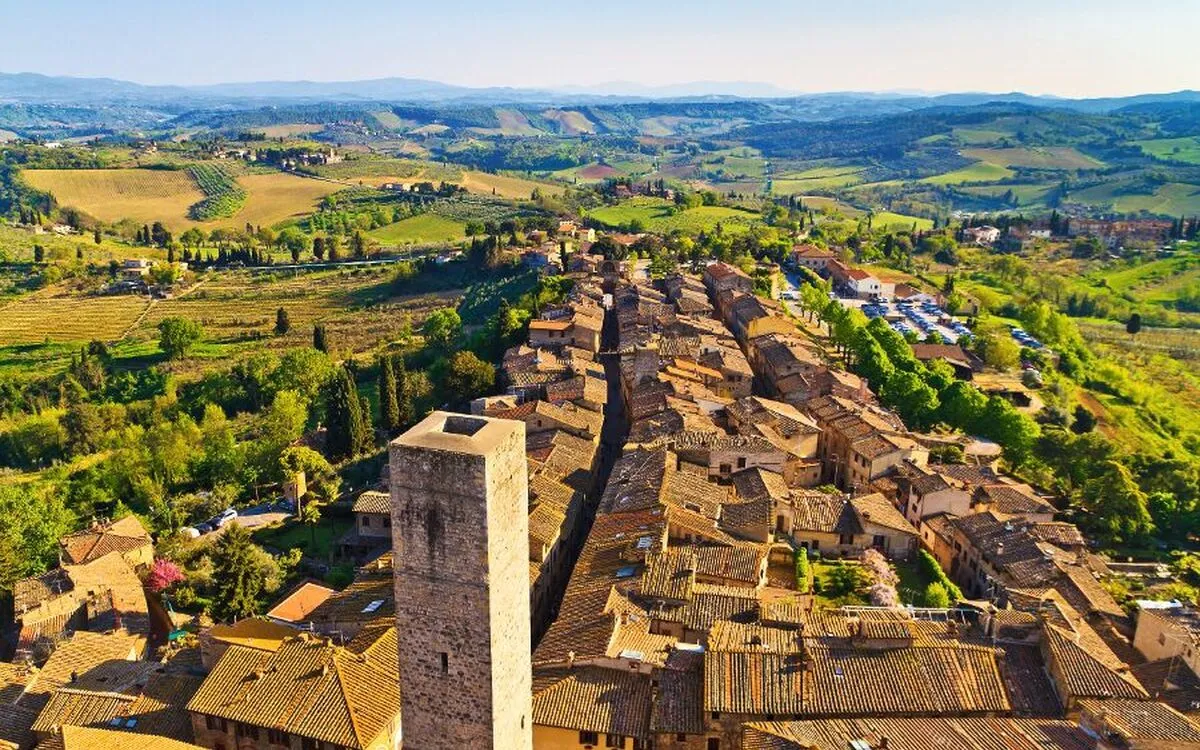 Luftbild einer italienischen Stadt mit mittelalterlichen Gebäuden und umliegender Landschaft.