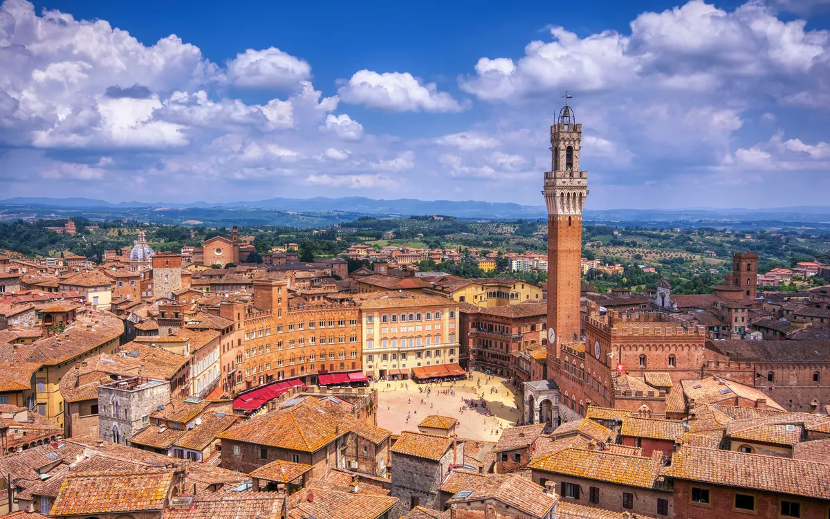 Luftaufnahme einer italienischen Stadt mit zentralem Turm und historischen Gebäuden.