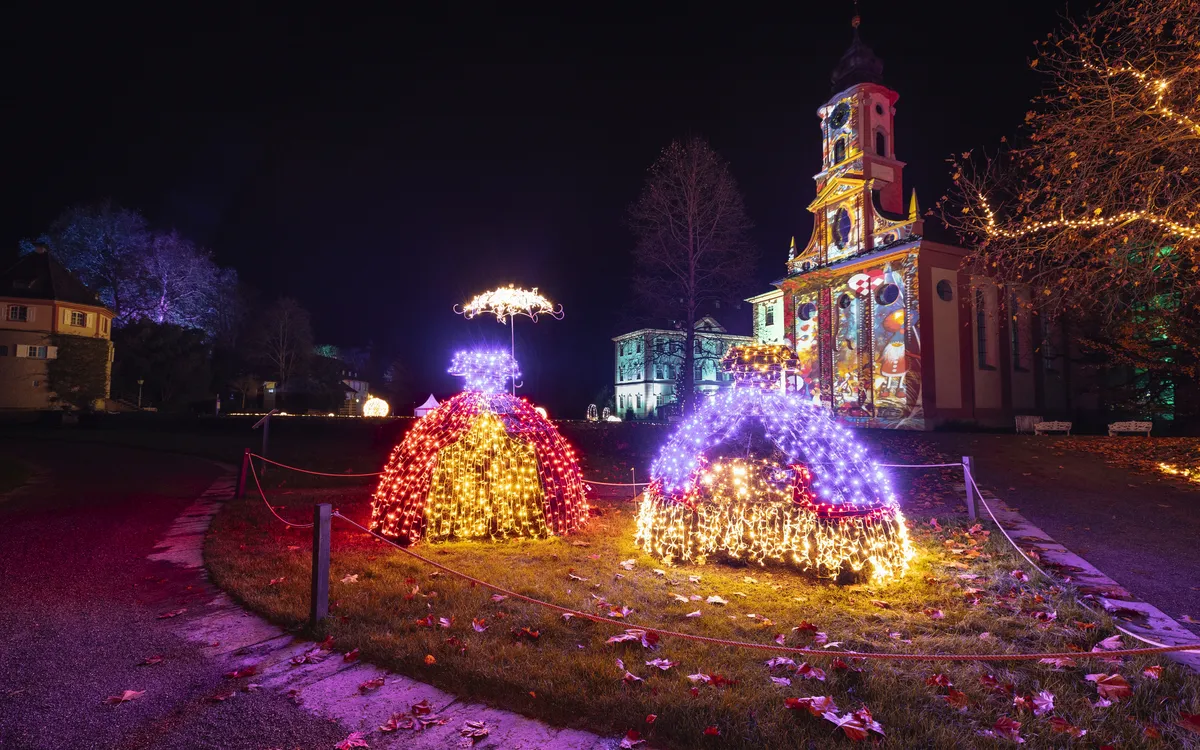 Weihnachtlich beleuchtete Szene im Garten mit Kirche bei Nacht