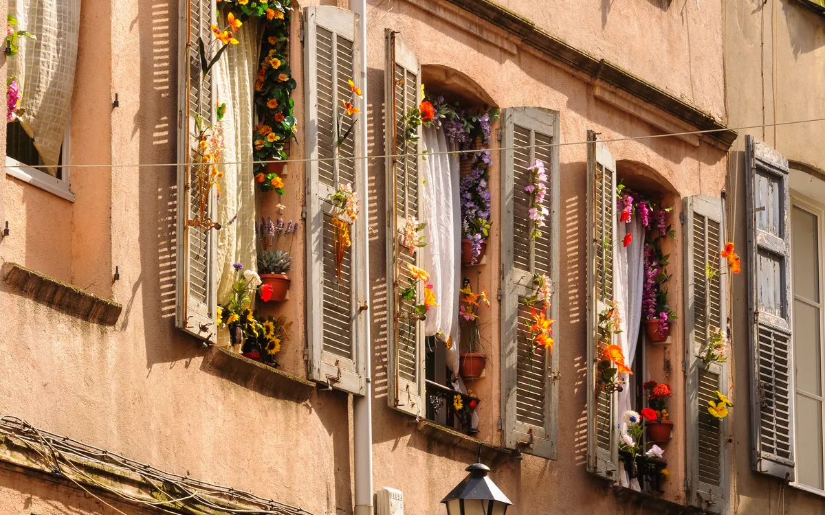 Fenster und Fensterläden mit Blumendekoration in Grasse, Provence-Alpes-Côte d’Azur, Frankreich.