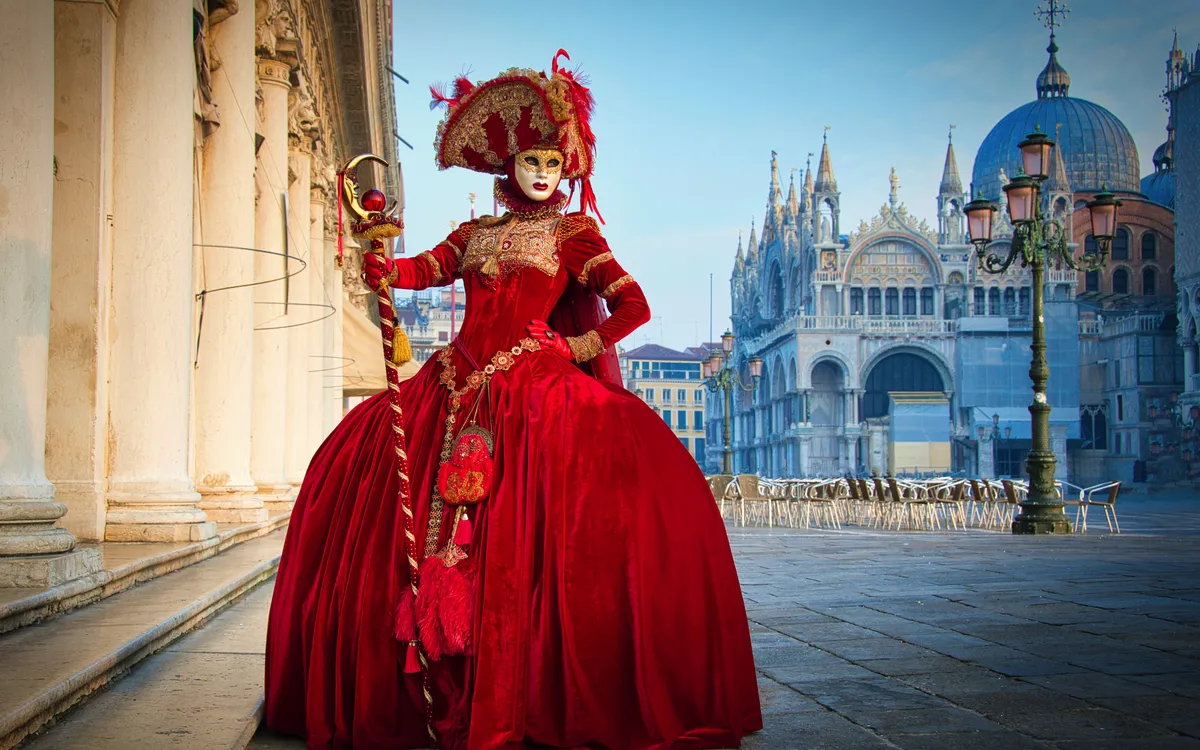 Person in opulenter venezianischer Kostümierung und Maske beim Karneval in Venedig.