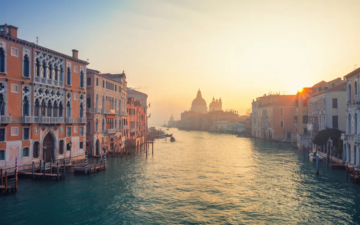 Kanal in Venedig bei Sonnenaufgang mit historischen Gebäuden.