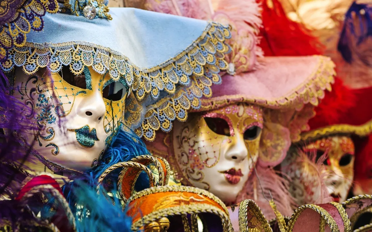 Personen in venezianischen Karnevalsmasken mit Hüten und Federn.