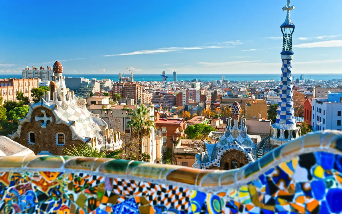 Blick auf die Stadt Barcelona mit Gaudí-Architektur im Vordergrund und dem Meer im Hintergrund.